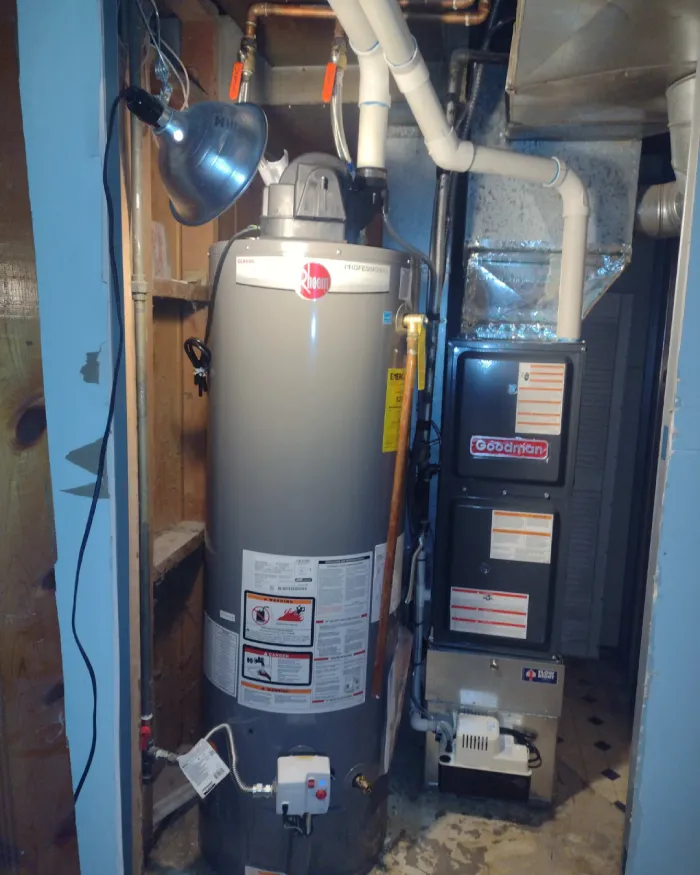 Tall gray gas water heater tank standing next to a residential HVAC furnace system in a utility closet.