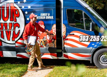 An HVAC technician holding a clipboard and gauge hoses while opening the side door of a wrapped JUMP HVAC service van.