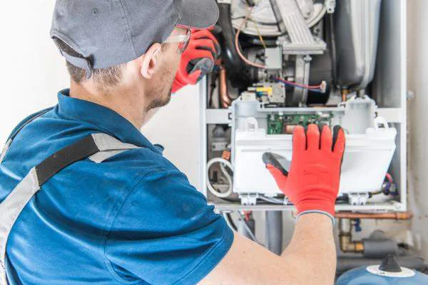 HVAC technician with safety glasses opening the control panel of a residential boiler.