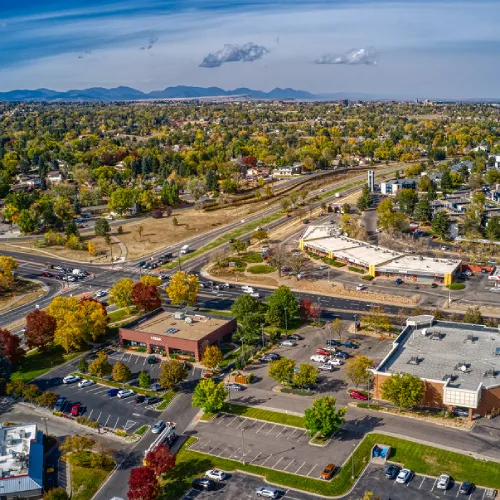 Aerial drone photograph of a suburban town landscape with autumn trees and distant intersections.